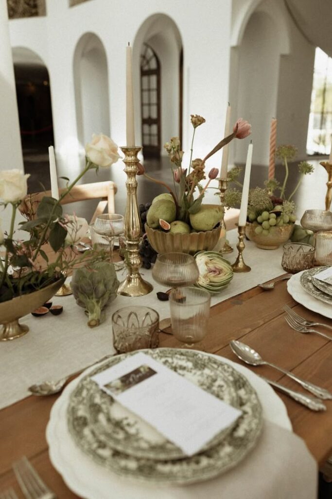 Elegante Tischdekoration mit Vintage-Tellern, Kerzen und floralen Tafelaufsätzen auf einem Holztisch - die perfekte Inspiration für jede Hochzeitsplanerin, die eine zeitlose Hochzeitsdekoration sucht.