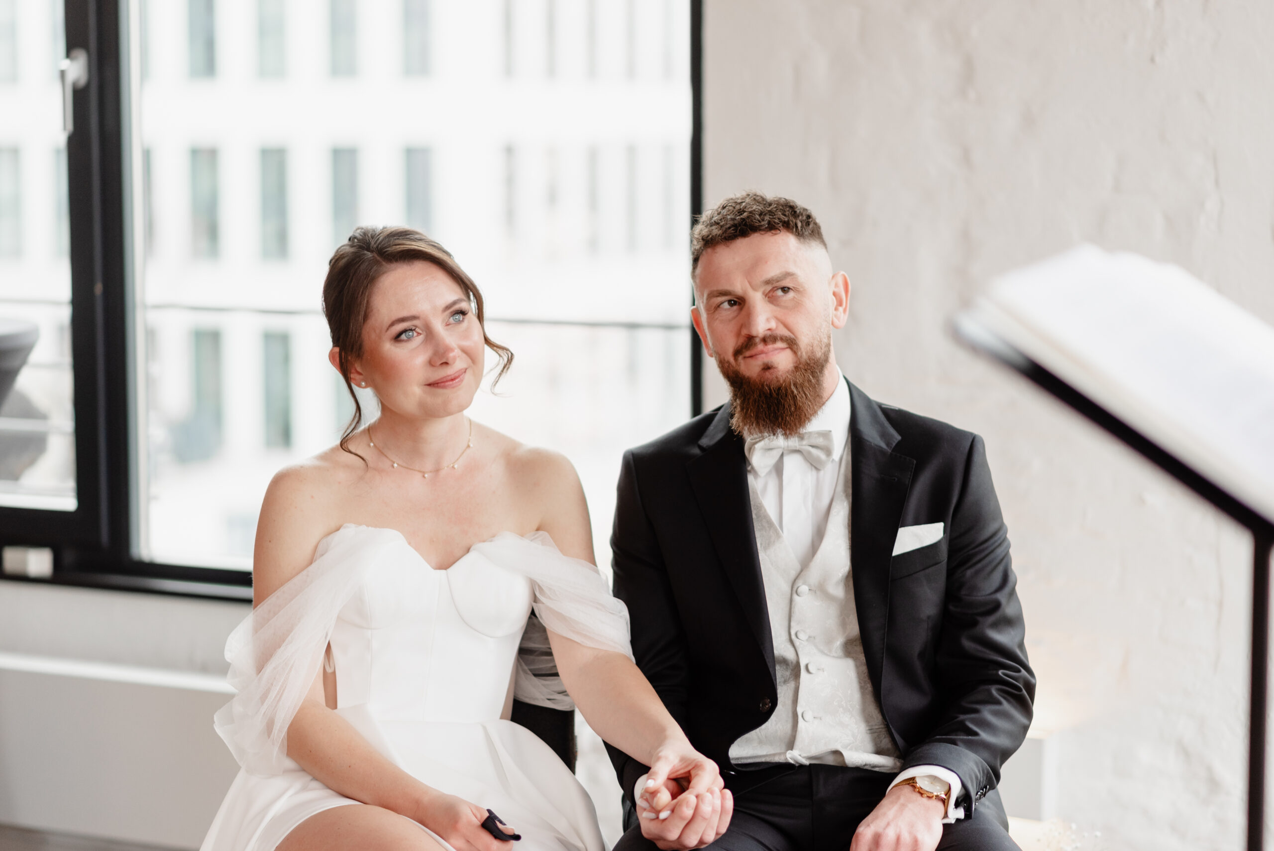 Braut und Bräutigam halten sich während einer Zeremonie im Saarland an den Händen und blicken mit ruhigem, emotionalem Gesichtsausdruck nach vorne.